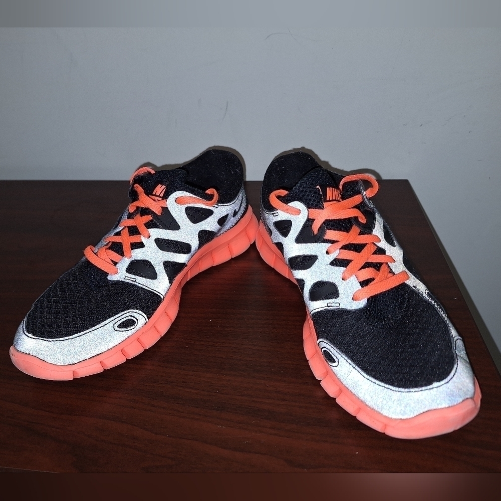 A pair of Nike Free Run 2. They Are Black With Orange Accents. Womens Size 6.5